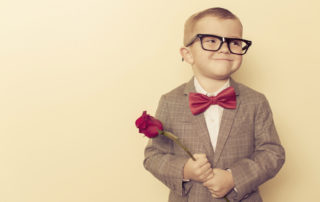 Boy in suit and glasses holding a rose