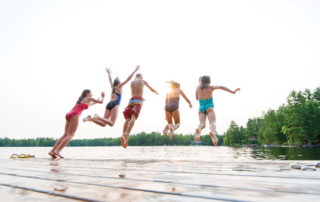 kids jumping into water from dock